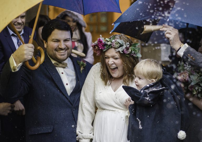Wedding party celebrating under umbrellas in joyful atmosphere