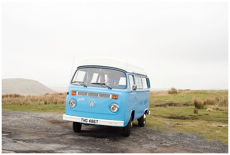 Blue vintage van parked on countryside road under cloudy sky