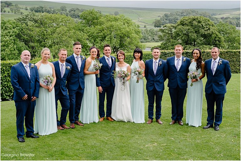 Wedding party posing in garden with scenic countryside view
