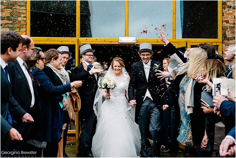 Bride and groom leaving wedding ceremony showered with confetti