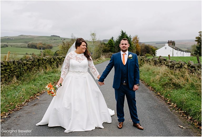 Bride and groom pose on scenic country road on wedding day