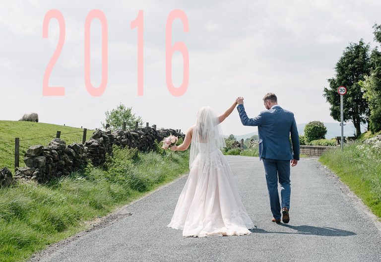 Bride and groom walking on country road under cloudy sky
