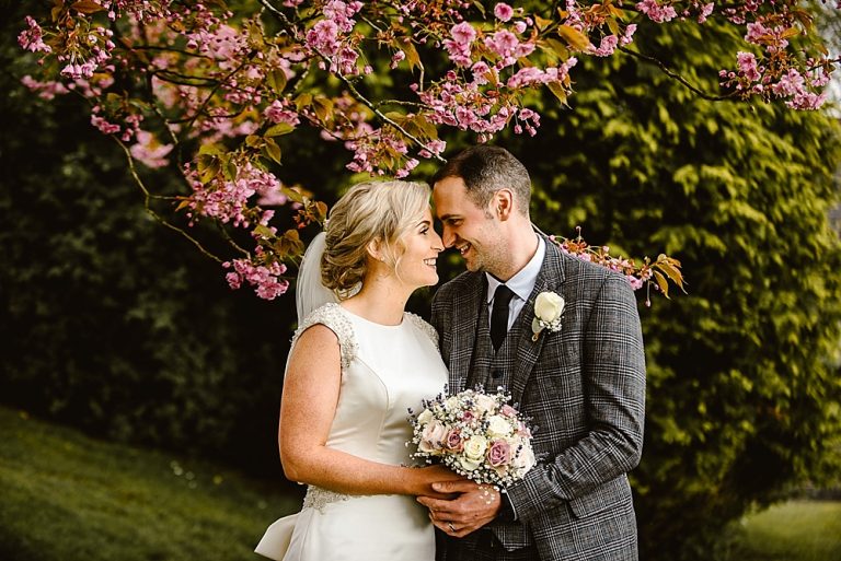 Bride and groom embracing under blooming pink flowers