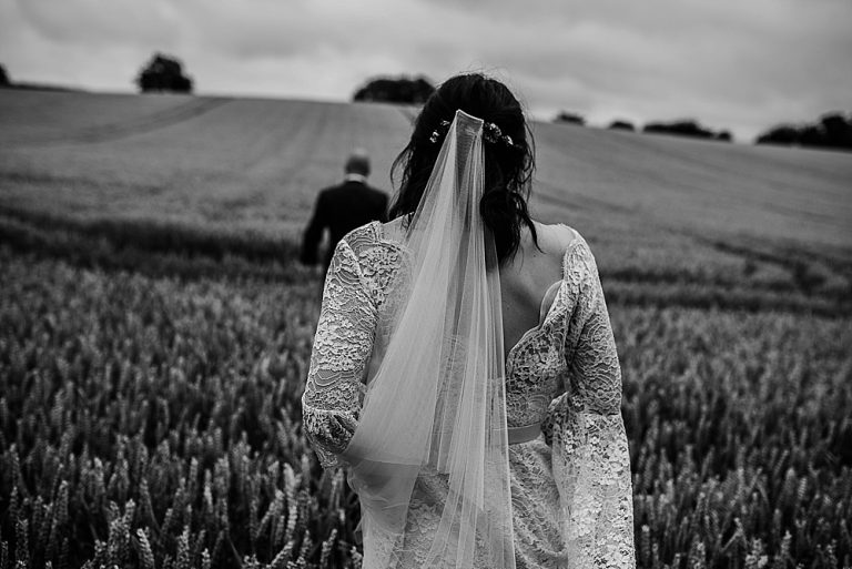Bride and groom walking through a scenic fields landscape