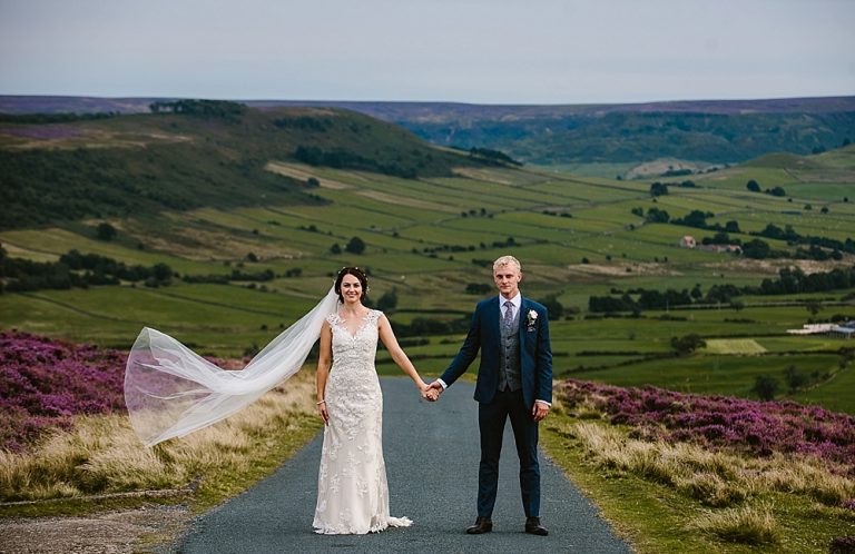 A couple in wedding attire in a picturesque countryside setting