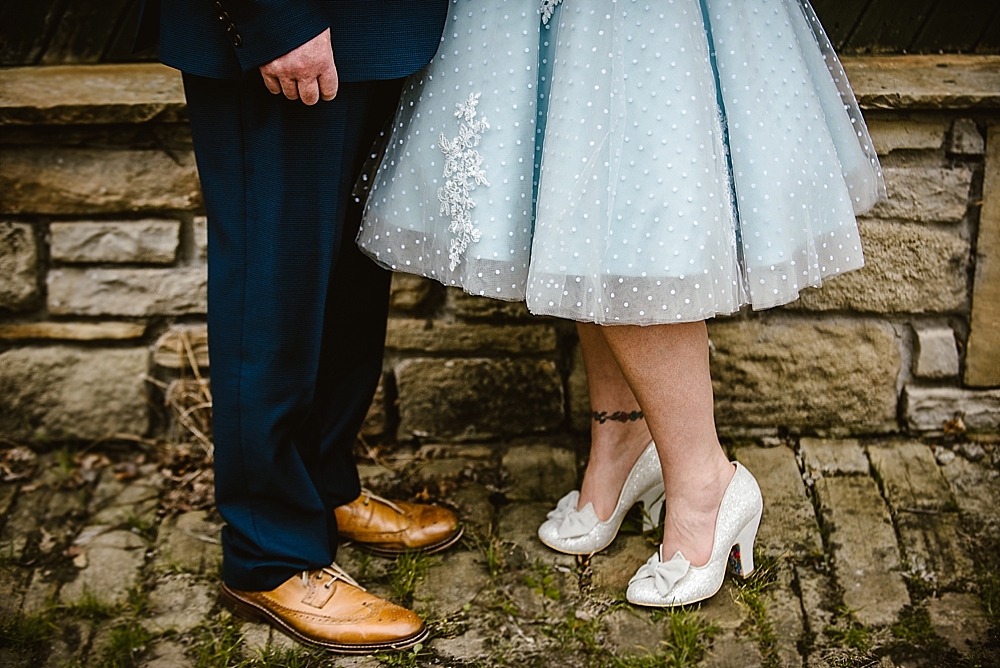 Formal couple's shoes on cobblestone path with stone wall background