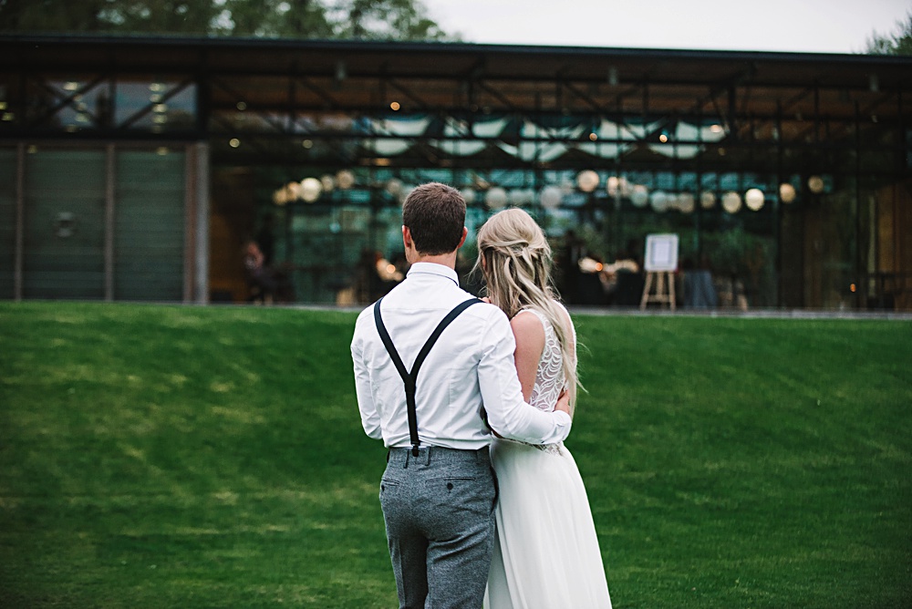 Newlyweds embrace in front of rustic wedding venue garden
