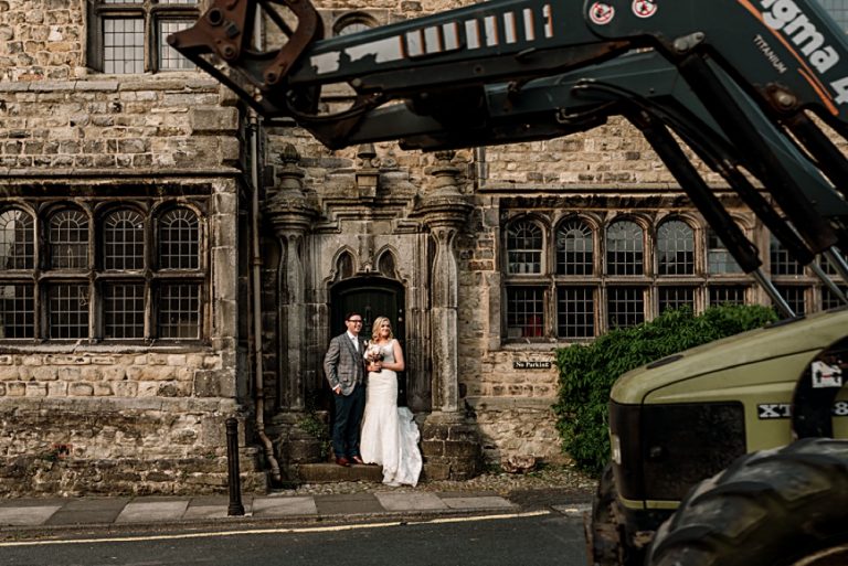 Wedding couple posing by historic stone building entrance