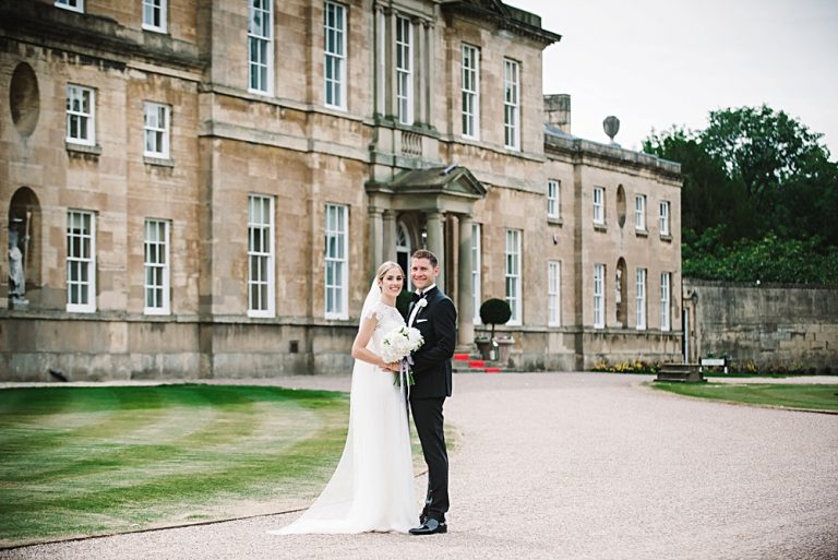 Bride and groom posing in front of elegant historic mansion