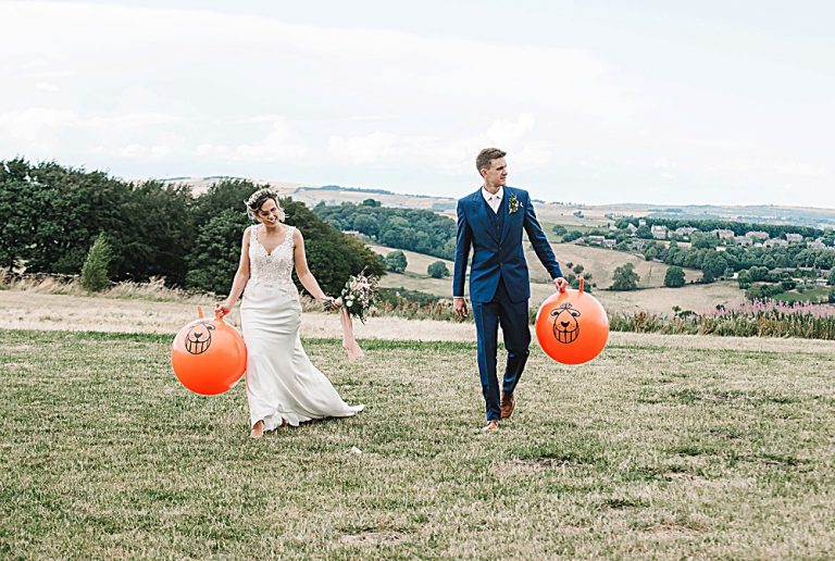 Bride and groom holding bouncy balls in a scenic field