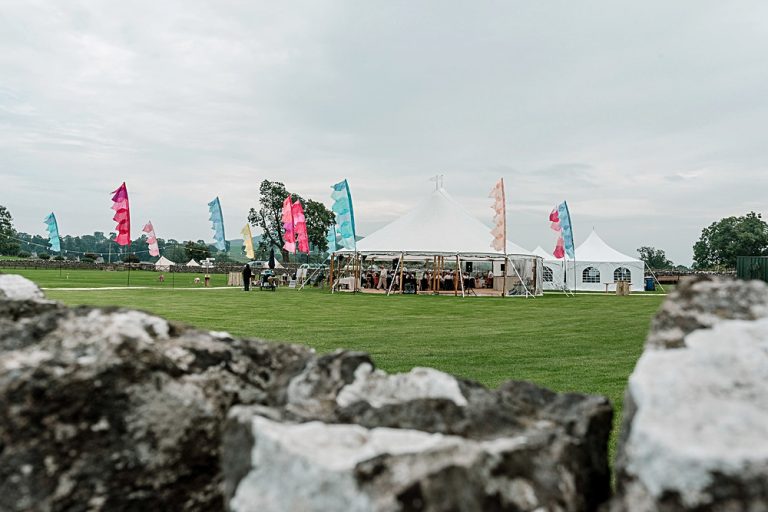 Countryside event marquee with colourful flags on green field