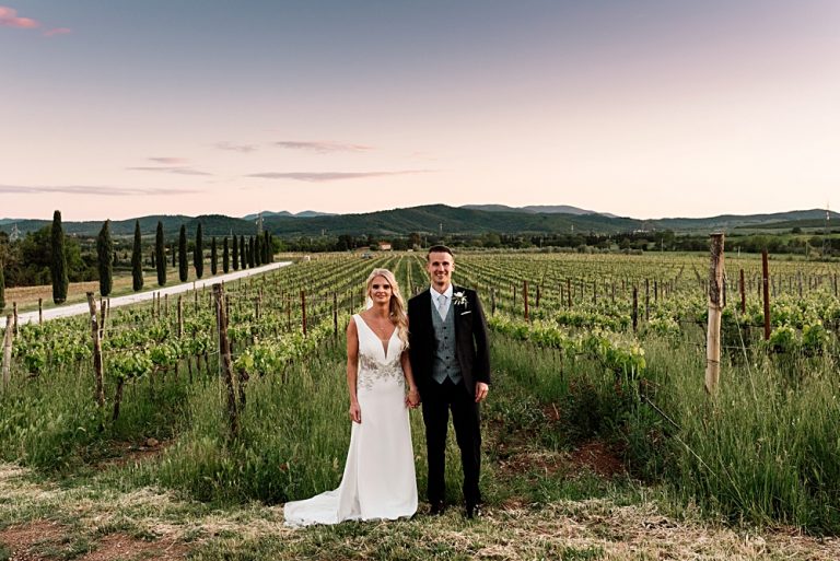 Bride and groom standing in scenic vineyard landscape