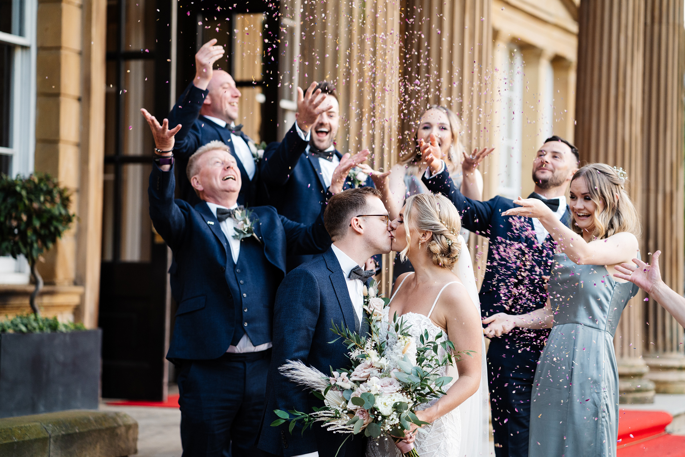 Bride and groom kiss surrounded by joyful celebration