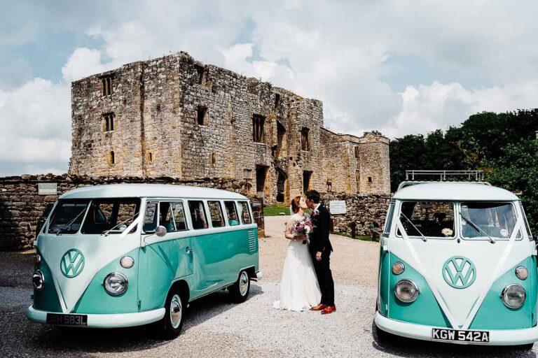 Classic wedding photo with vintage vans near historic castle.