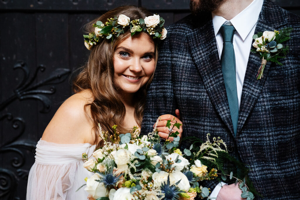 Bride smiling with bouquet and groom in checkered suit