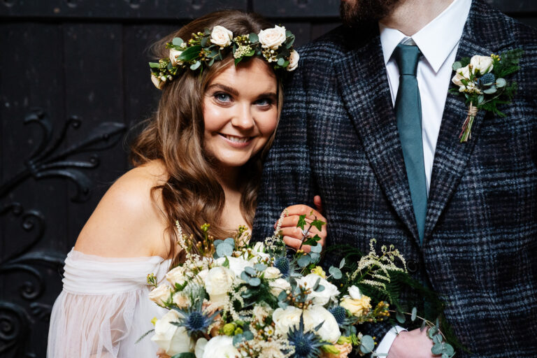 Bride smiling with bouquet and groom in checkered suit