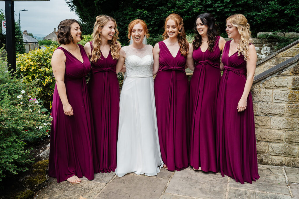 Bride with bridesmaids in burgundy dresses outside venue