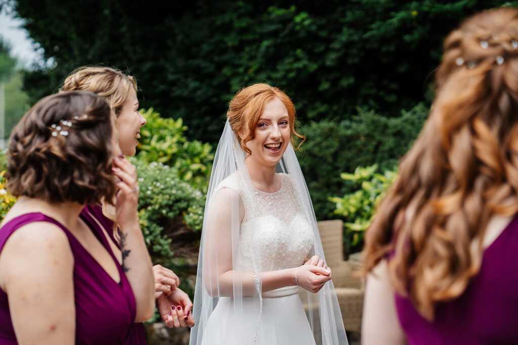 Bride smiling with bridesmaids in garden setting