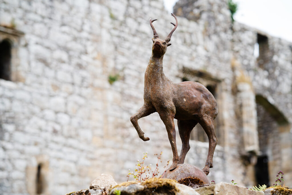 Bronze antelope statue in front of ancient stone building The Priests House in Barden, North Yorkshire