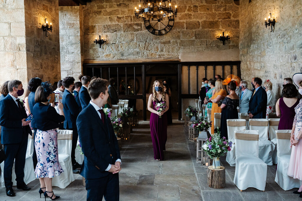 Indoor wedding ceremony with guests and flower arrangements
