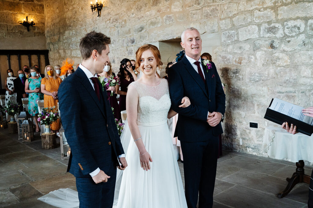 Bride smiling at a groom during a wedding ceremony indoors The Priests House in Barden, North Yorkshire