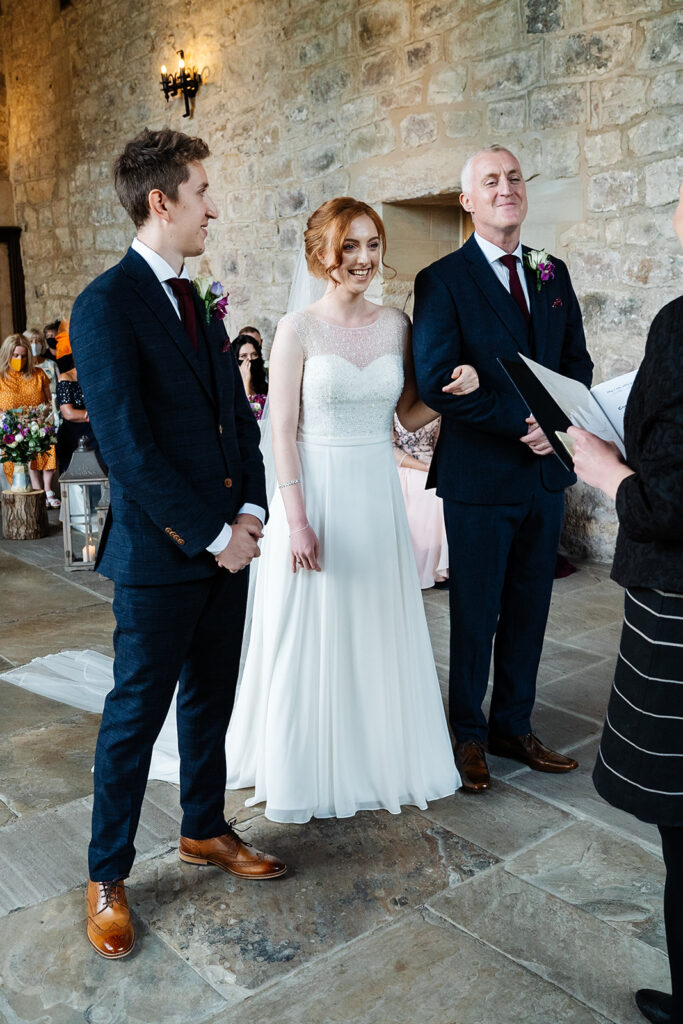 Bride and groom smiling during wedding ceremony indoors. The Priests House in Barden, North Yorkshire