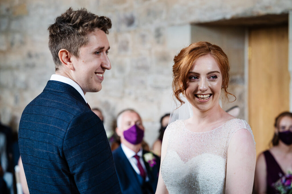 Bride and groom smiling during their wedding ceremony indoors The Priests House in Barden, North Yorkshire