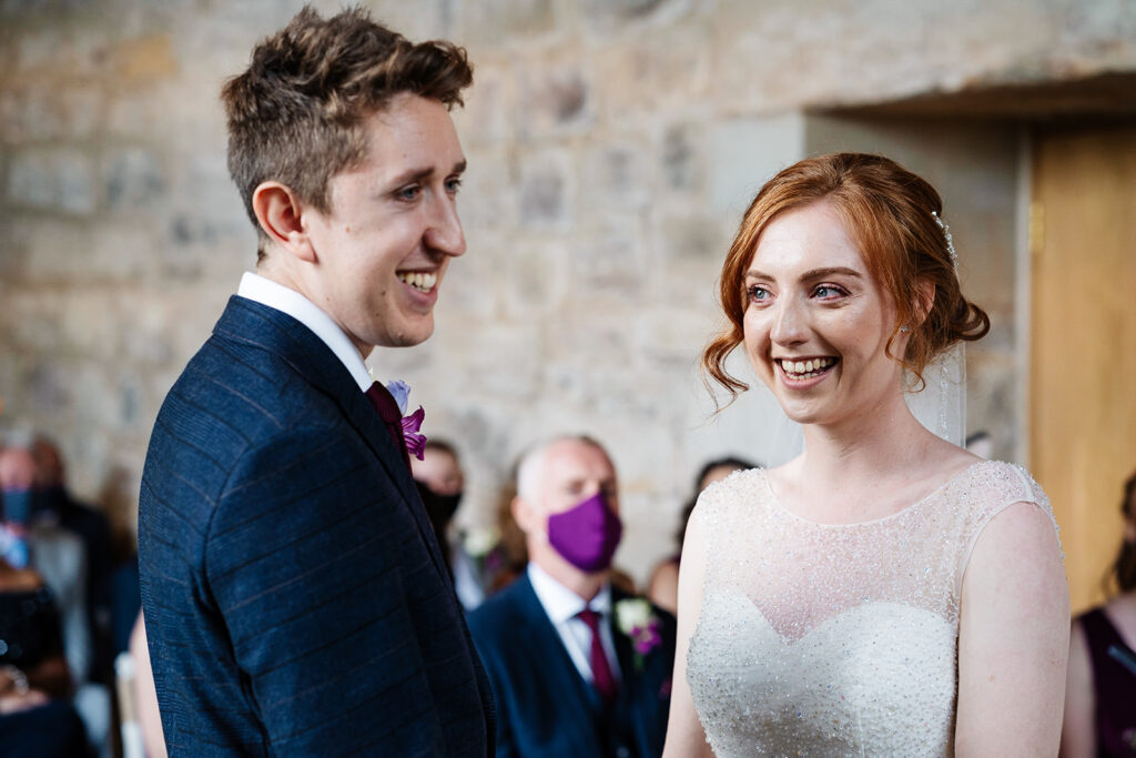 Bride and groom smiling during a wedding ceremony indoors