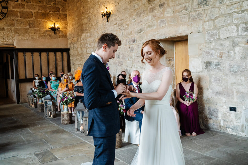 Bride and groom exchange rings in rustic wedding ceremony The Priests House in Barden, North Yorkshire