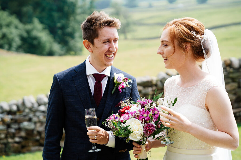 Bride and groom laughing together in scenic countryside setting
