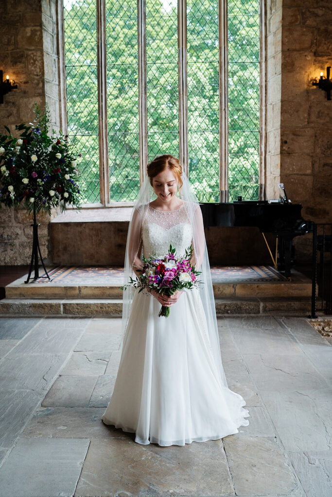 Bride in elegant white dress holding a vibrant bouquet indoors The Priests House in Barden, North Yorkshire