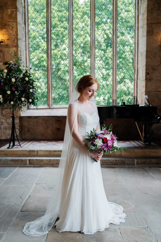 Bride in elegant wedding dress holding bouquet indoors The Priests House in Barden, North Yorkshire