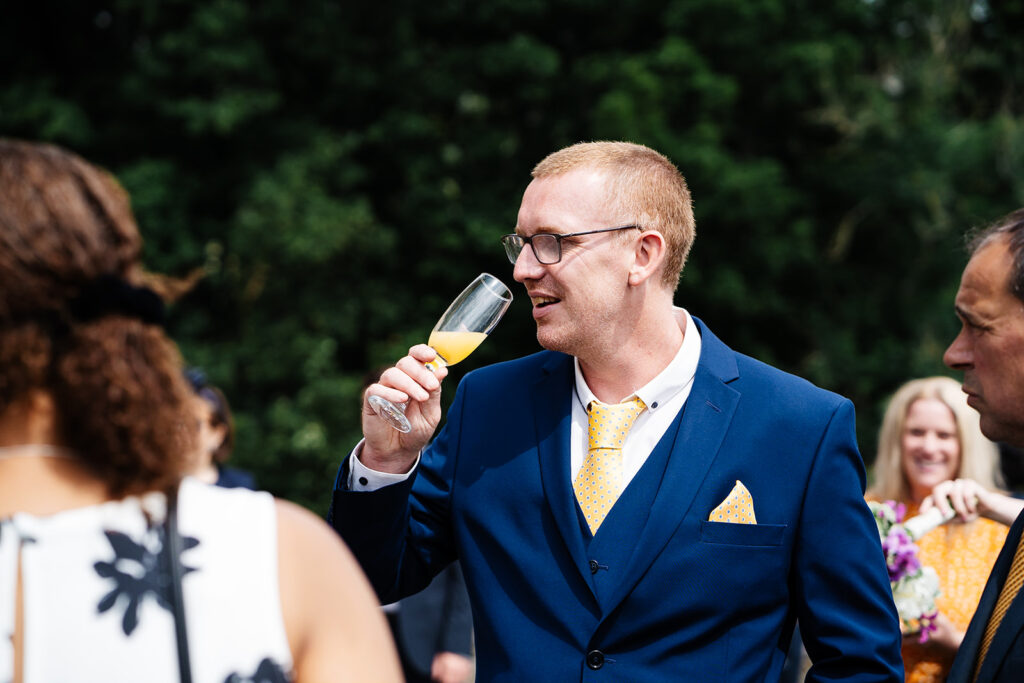 Man in blue suit enjoying a drink at outdoor event