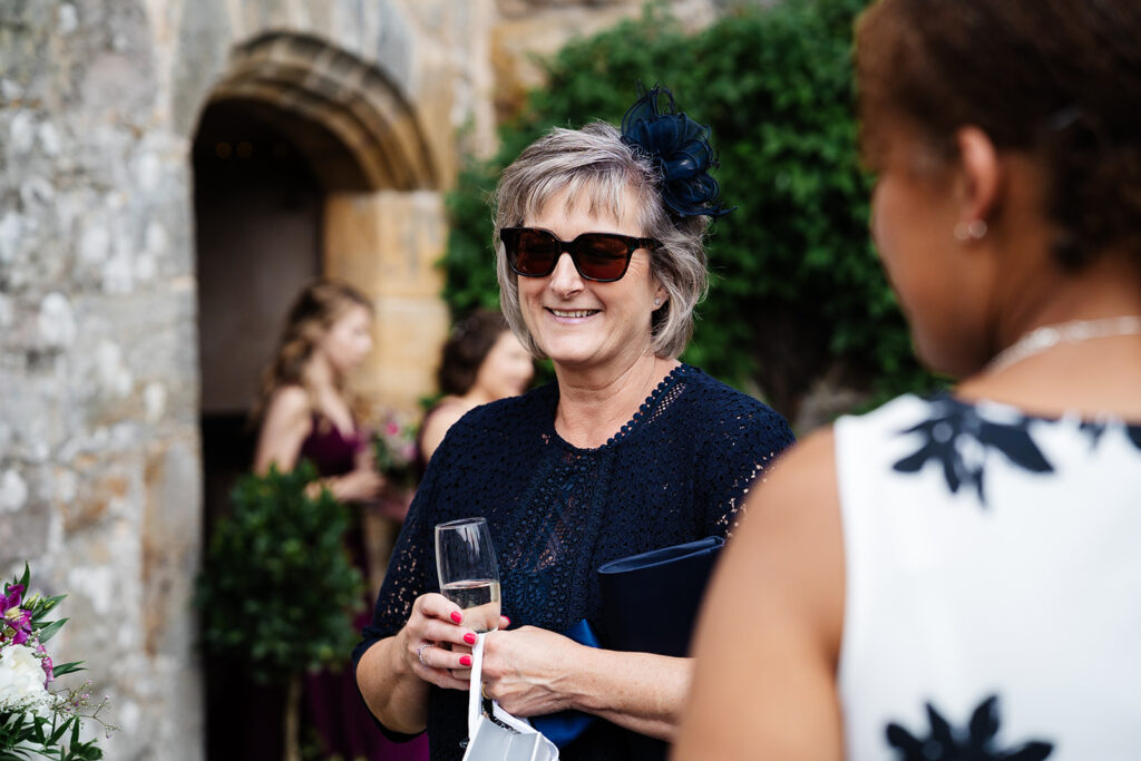 Woman in sunglasses holding glass at outdoor gathering