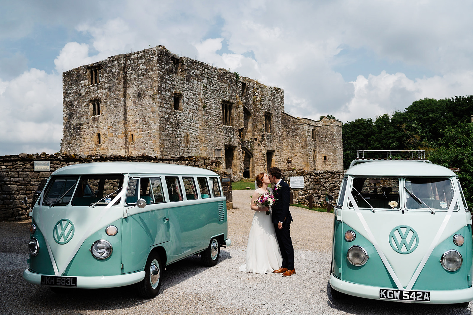 Bride and groom with vintage vans at historic stone castle