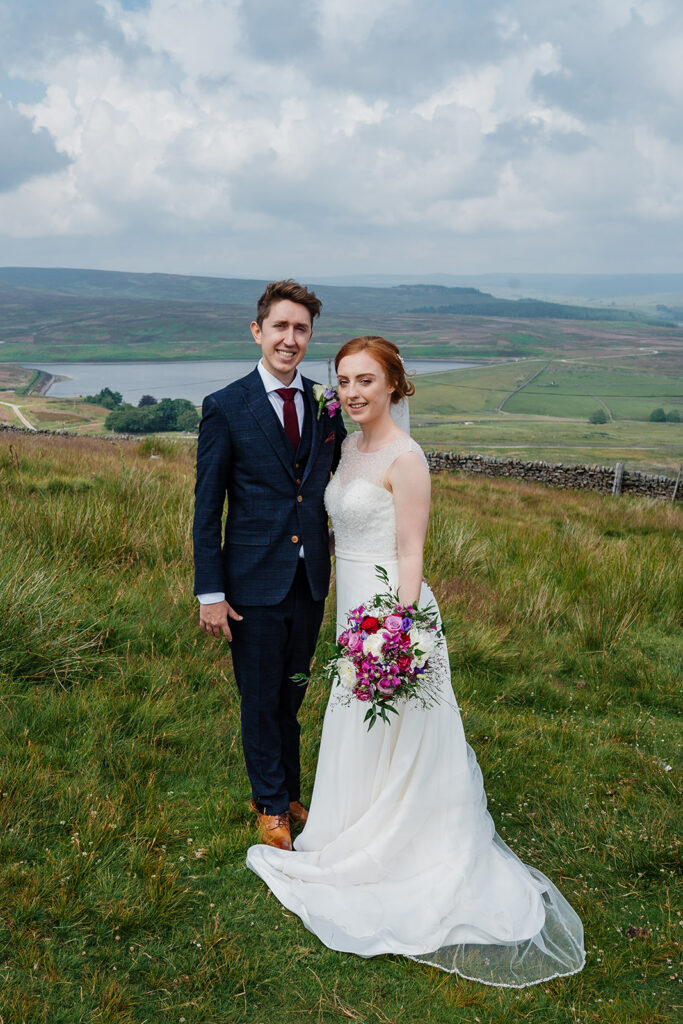 Bride and groom standing in scenic countryside landscape