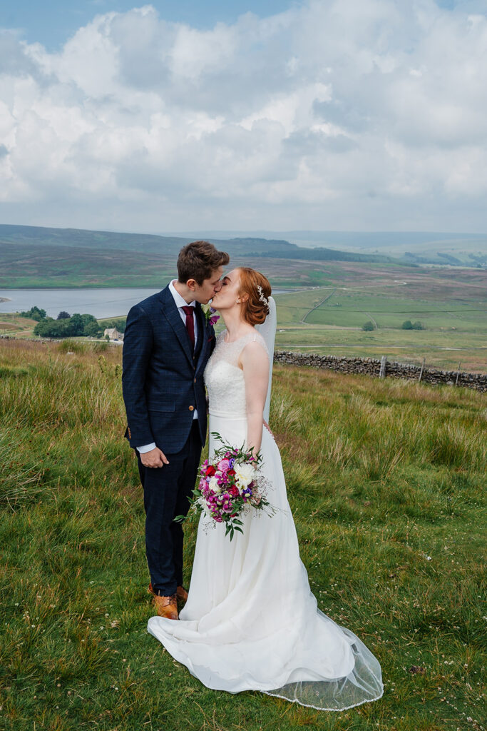 Bride and groom kiss in scenic countryside setting Yorkshire wedding