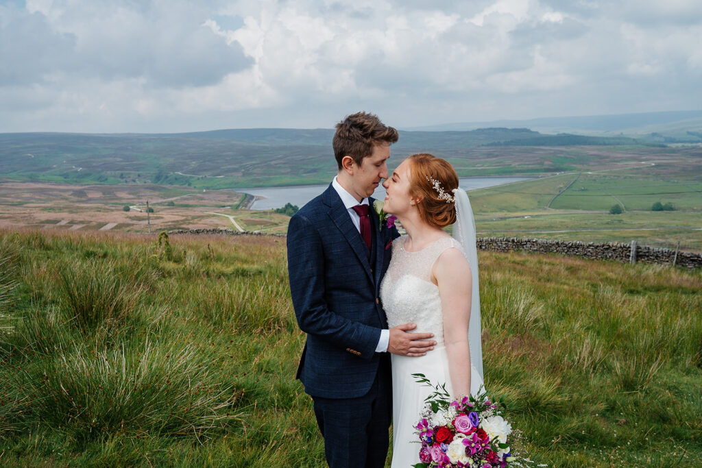 Bride and groom embrace in scenic countryside setting