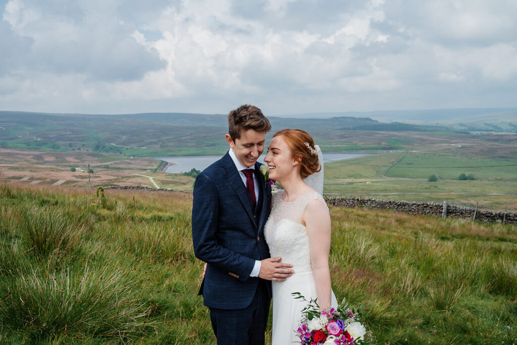 Bride and groom embrace on scenic countryside wedding day