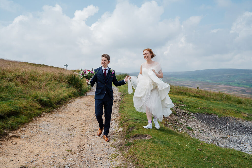 Bride and groom happily walking on a scenic countryside path