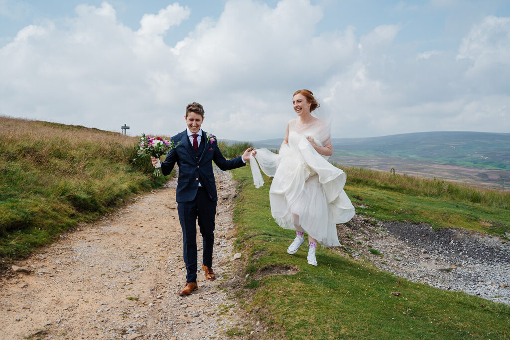 Bride and groom walking happily on a scenic countryside path
