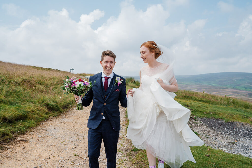 Bride and groom walking outdoors with flowers and smiles