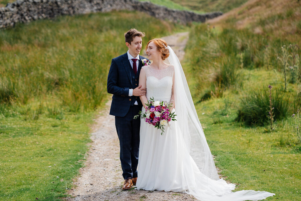 Bride and groom walking on a scenic countryside path
