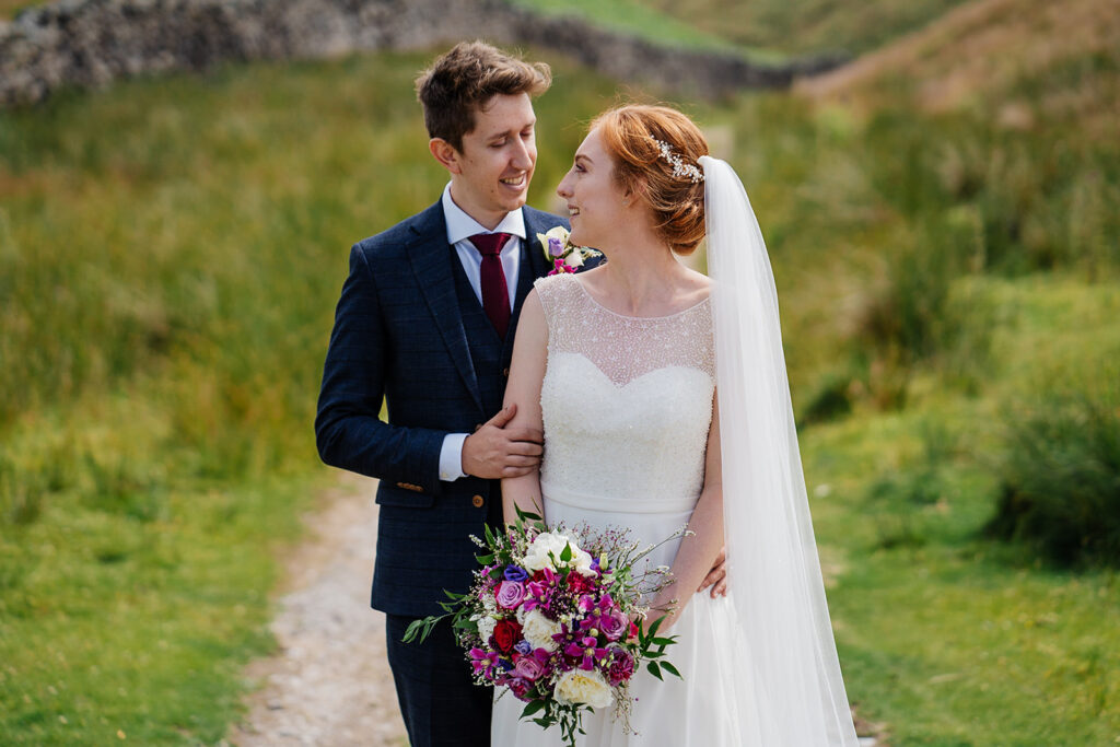 Bride and groom smiling on a scenic countryside path