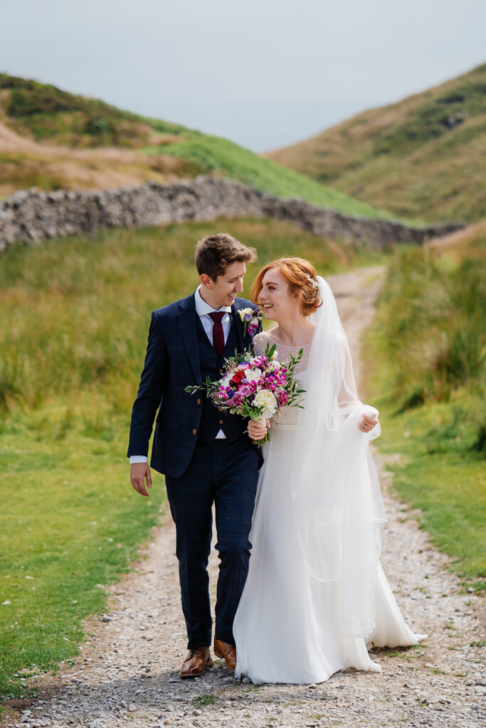 Bride and groom walking on scenic path with bright flowers