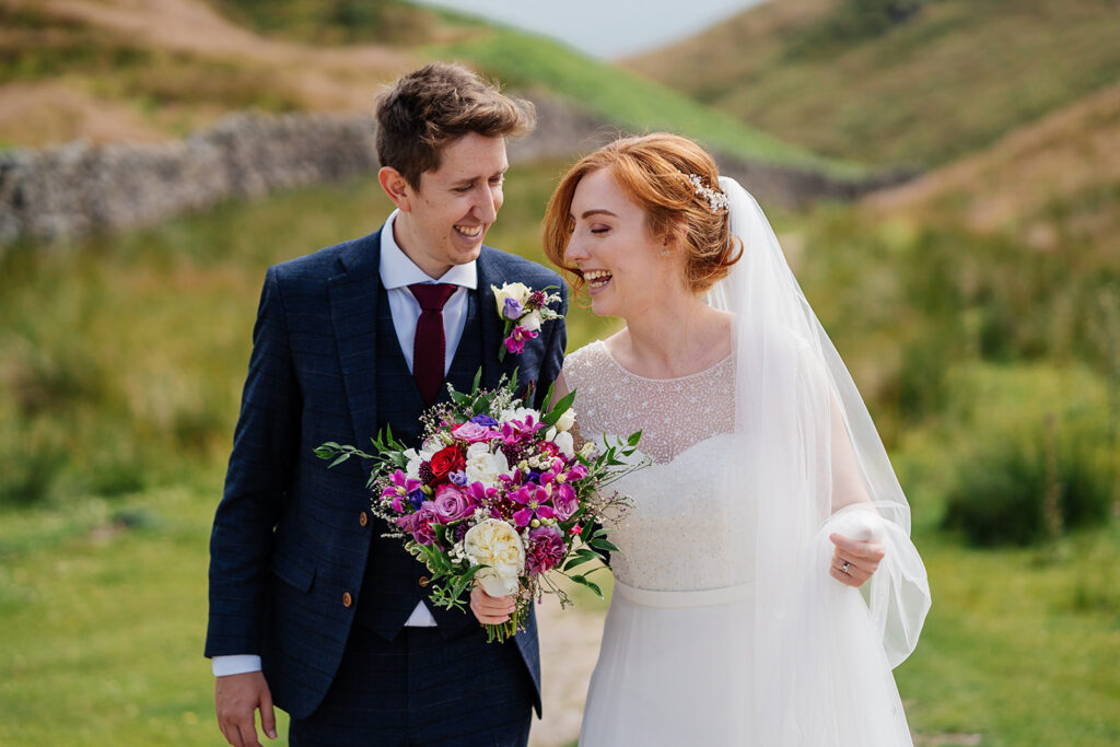 Bride and groom smiling in scenic outdoor wedding portrait