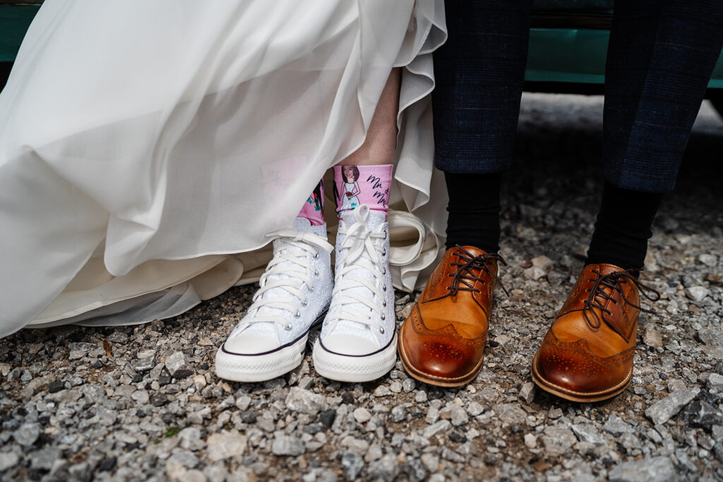 Bride in white trainers next to groom in brown leather shoes