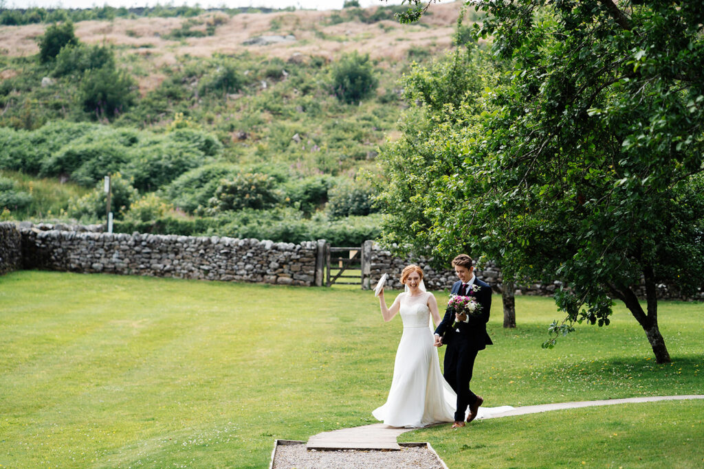 Bride and groom walking in a scenic garden pathway at wedding
