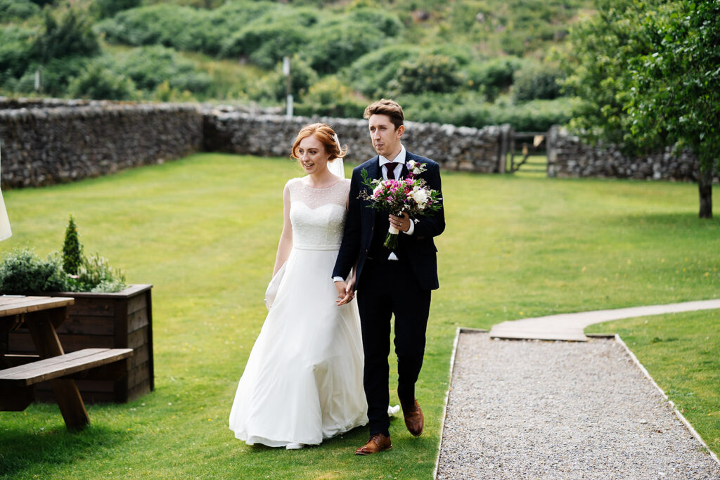 Bride and groom walking in lush garden on their wedding day