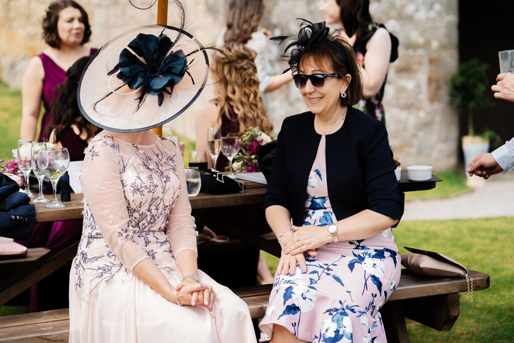 Women in elegant hats at a formal outdoor gathering